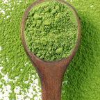 A wooden spoon of bright green KaLOHAS organic kale powder resting on fresh kale leaves